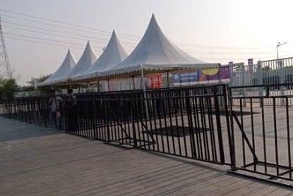 Barikade hitam dan tenda di area luar stadion saat senja